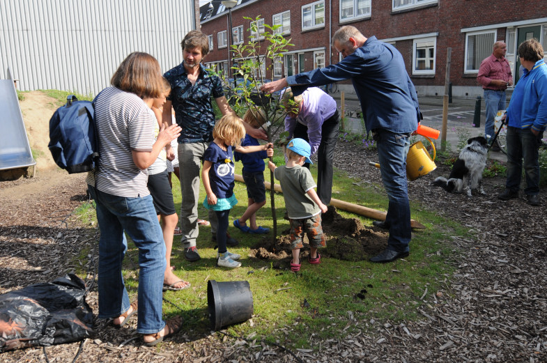 nils berndsen plant de boom. bewoners en kinderen houden de boom vast.